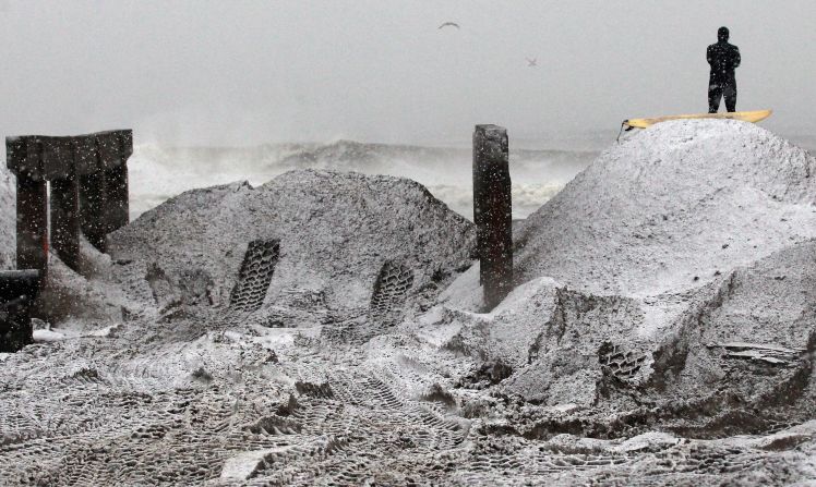 ''Mandog'' watches the surf from a pile of sand beside the destroyed boardwalk in Rockaway area on Wednesday. Sand had been collected from the streets and placed on the beach to clear the roads and to help prevent possible storm surge. 