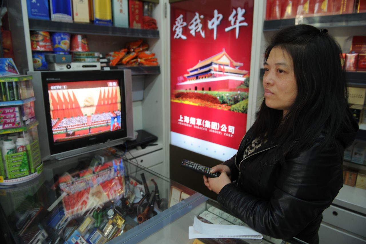 A woman watches the Party Congress on television from her cigarette shop in Shanghai.