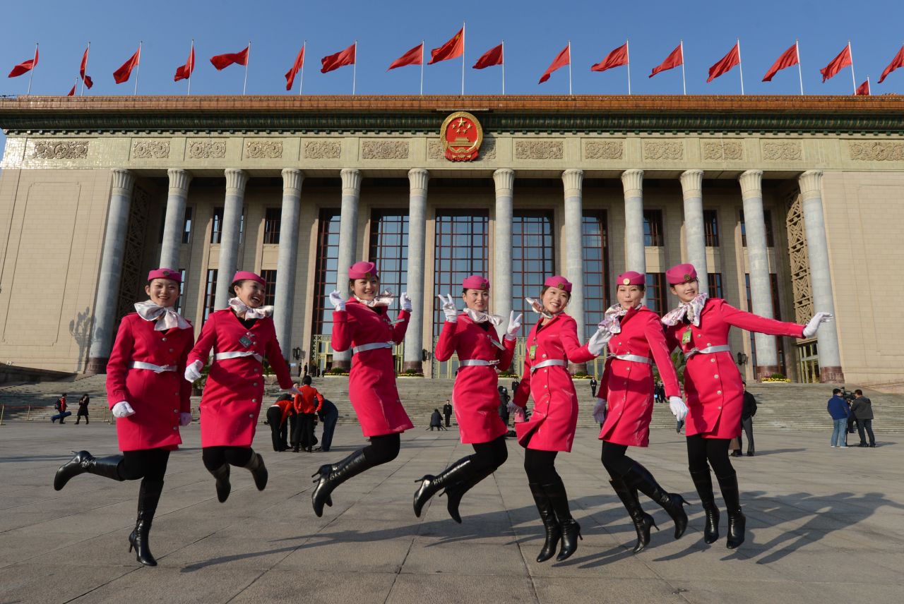 Chinese hostesses jump for the cameras before the Party Congress' opening session in Beijing.