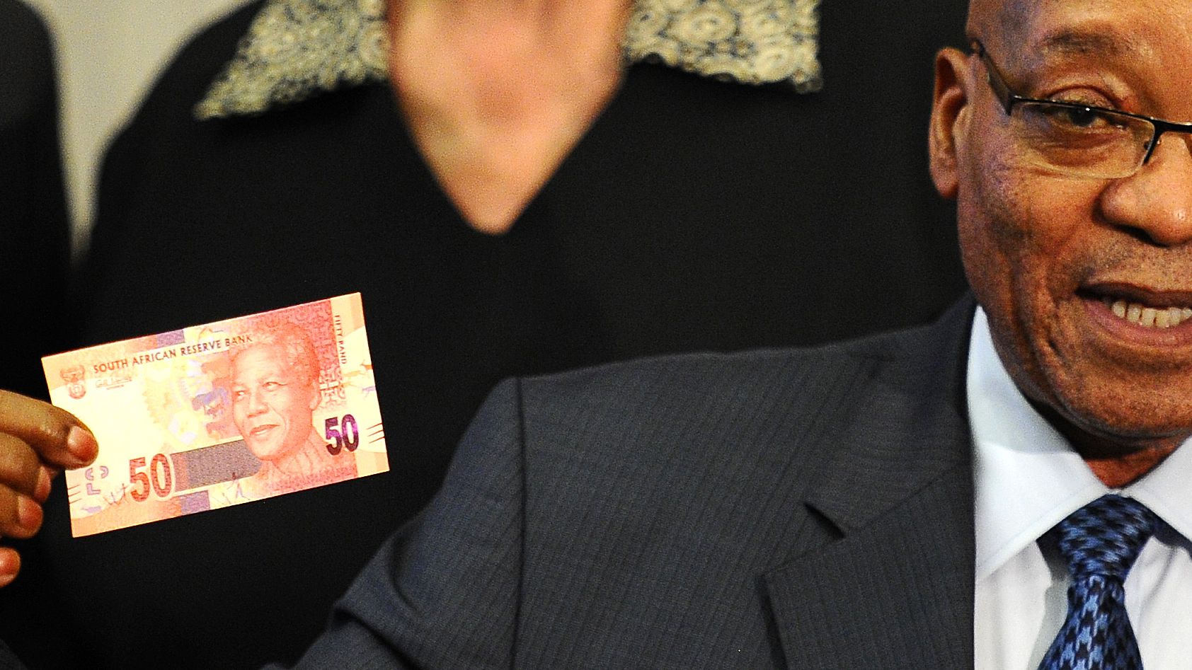 South African President Jacob Zuma shows a note featuring the country's former president Nelson Mandela.
