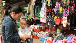 A mother sits with her child outside a shop on a street in Shanghai on May 23, 2012. China's economic growth will continue to ease this year, presenting policy makers in Beijing with the challenge of preventing an excessively abrupt slowdown, the World Bank said in a report.  