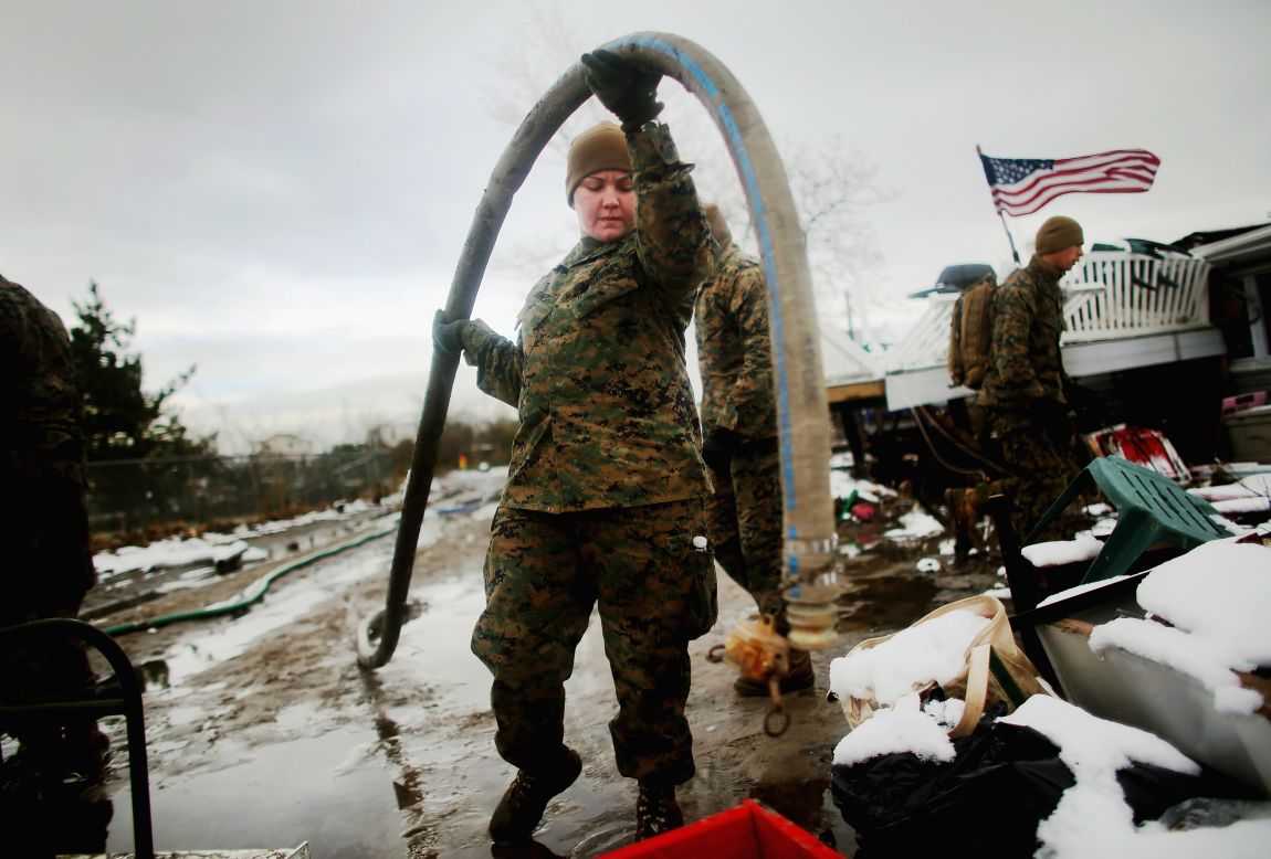 Lance Cpl. Trina Azevedo carries a hose to pump out floodwater in Queens.
