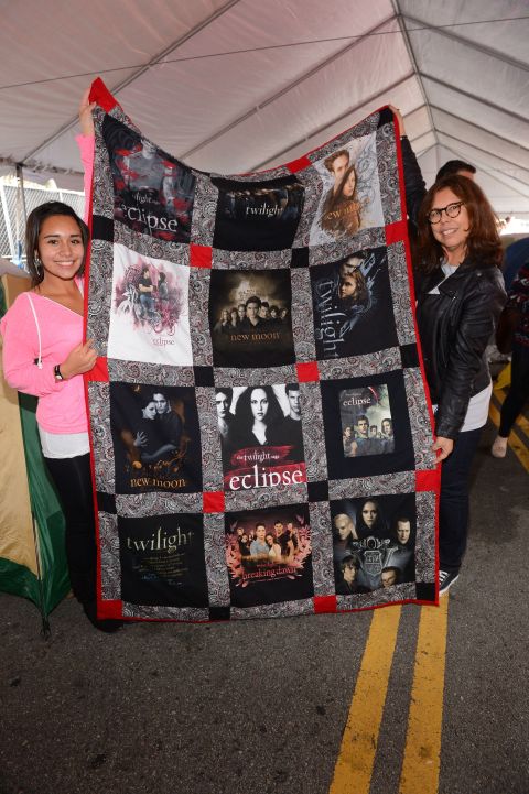 Two fans hold up a "Twilight" quilt.