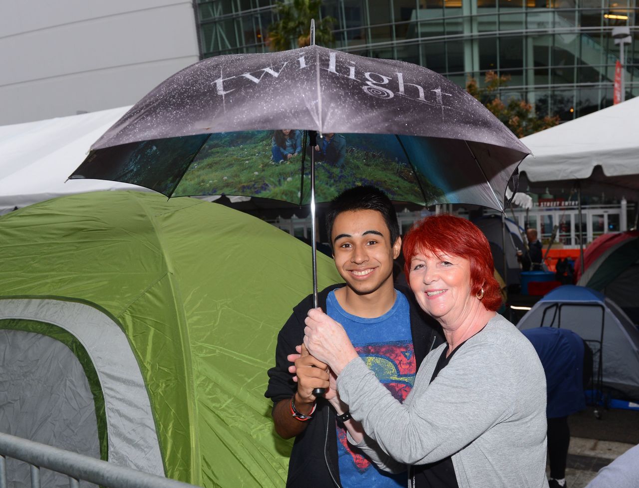 Two fans brave the rain with a "Twilight" umbrella at tent city.