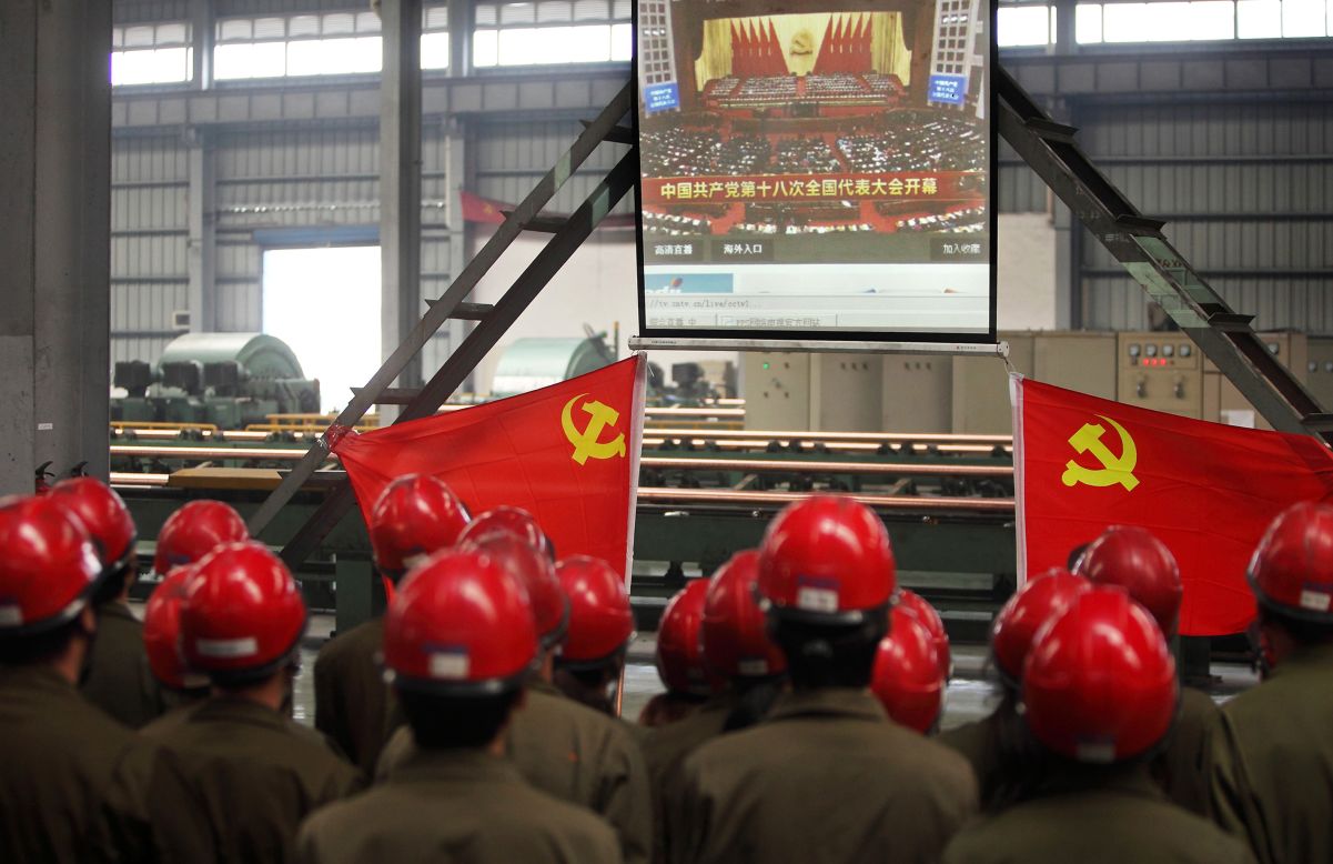 Workers gather to watch Hu's address to the Communist Party Congress. Hu called for stepped-up political reform and a revamped economic model on the first day of the congress.