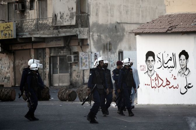 Bahraini riot policemen walk past graffiti reading in Arabic: 'Peace on our martyrs' as they try to disperse protesters. The teenager was killed as police attempted to stop pposition supporters from joining a mass during weekly Friday prayers. 