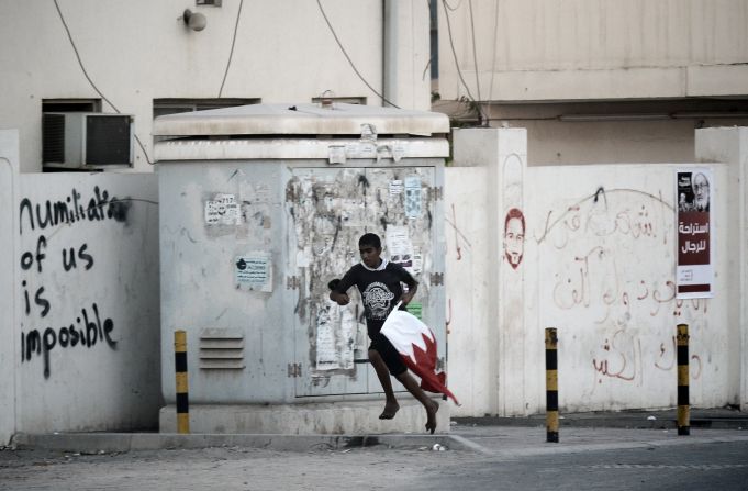 A Bahraini Shiite protester runs for cover from riot police after a crackdown on an anti-government demonstrator. They were protestsing against the killing of 16-year old Ali Abbas Radhi in the village of Diraz, west Manama on  November 9, 2012. 