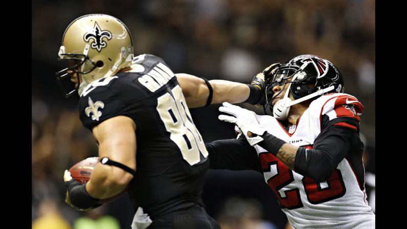 Jimmy Graham of the Saints stiff arms Thomas DeCoud of the Falcons on his way to the end zone for a touchdownon Sunday.
