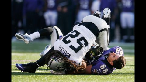 Tight end Dennis Pitta of the Ravens loses his helmet after catching a pass and being tackled by outside linebacker Philip Wheeler of the Raiders during the first half on Sunday.
