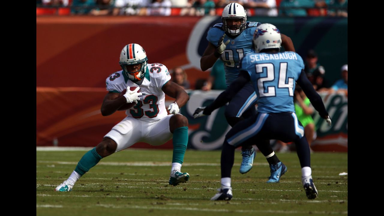 Running back Daniel Thomas of the Dolphins runs against Coty Sensabaugh of the Titans on Sunday.