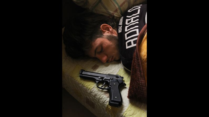 Syrian opposition fighter Bazel Araj, 19, sleeps next to his pistol in Aleppo on November 11.