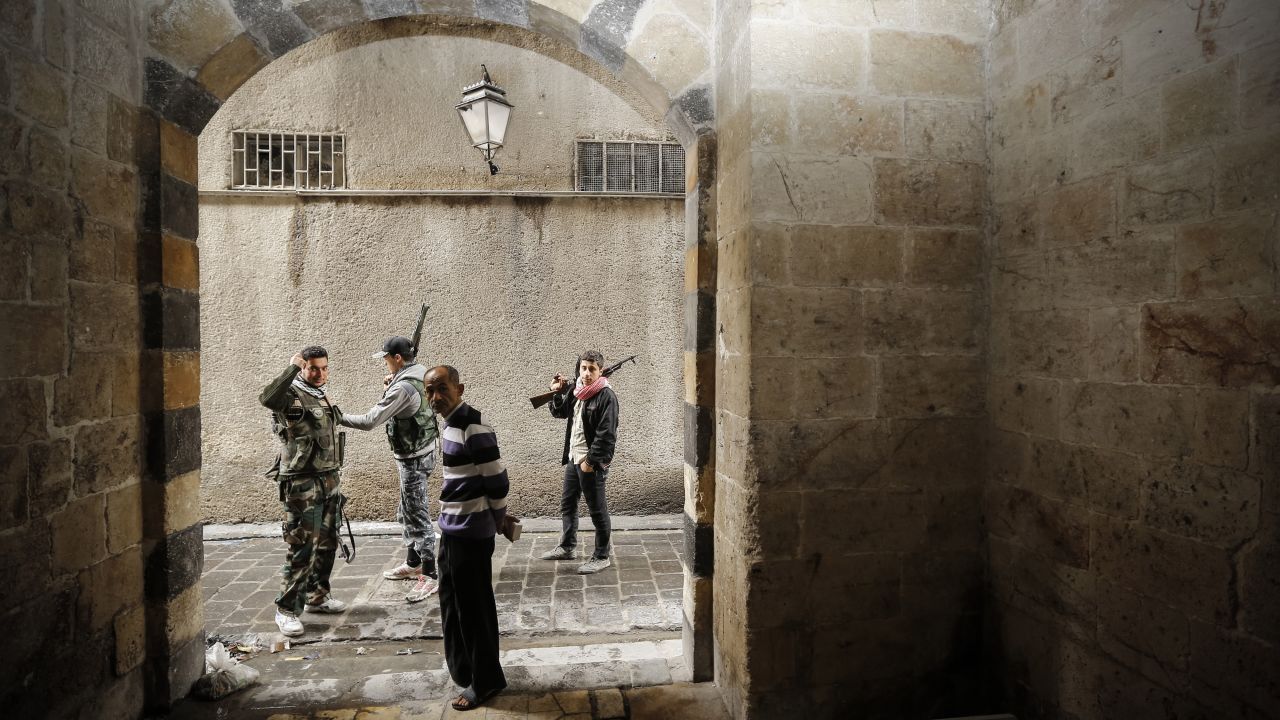 Syrian opposition fighters pass an old man as they patrol the northern city of Aleppo on November 11. 
