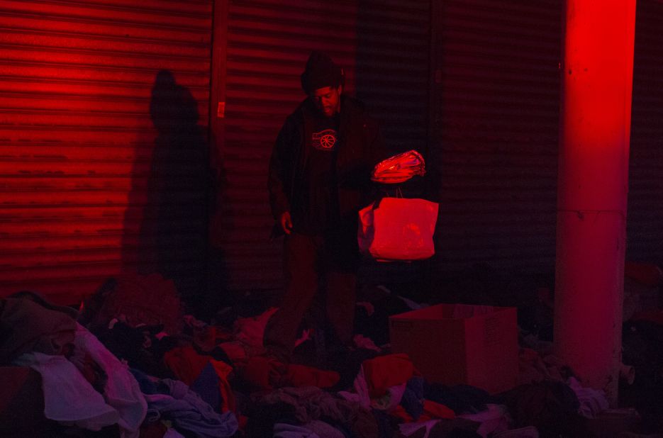 A man looks through donated clothes and supplies at nightfall Monday in Rockaway.