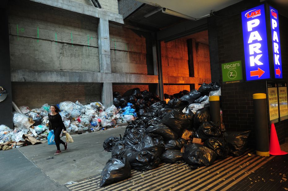 A woman makes her way past trash piles in Lower Manhattan on Monday. 