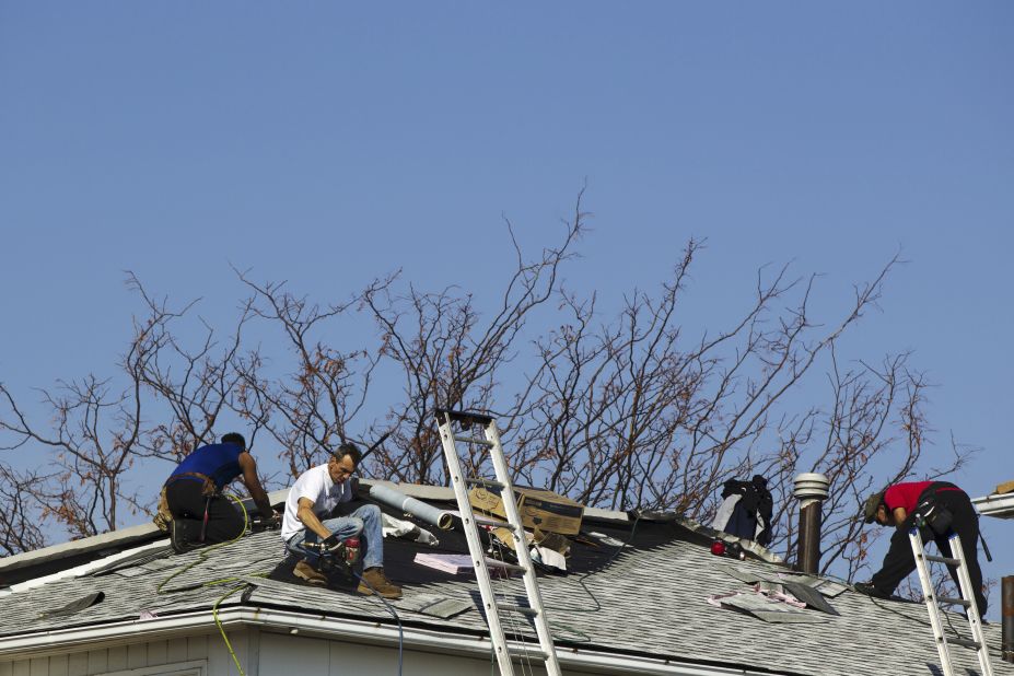 Roofers repair damage Monday on a home in the Annadale neighborhood of Staten Island.