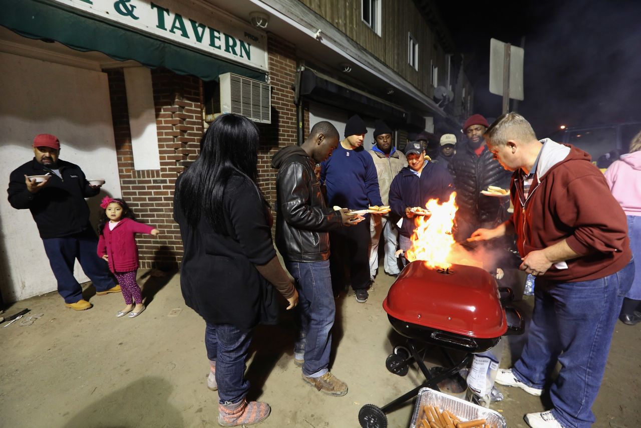 People gather for donated food beneath a spotlight in an area still without power on Monday in Rockaway.