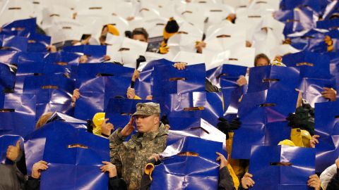 A member of the military stands at attention as fans hold up colored posters that made up the colors of the American flag during the performance of the national anthem before the Steelers-Chiefs game on Monday. Veterans Day was on Sunday, November 11.