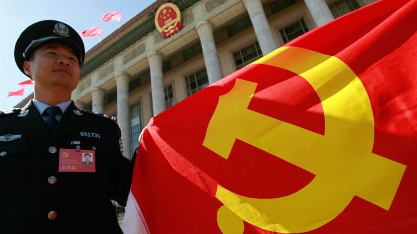 A Chinese policeman holds a Chinese Communist Party flag to show his supports to the party during the 17th Communist Party Congress in Beijing 15 October 2007. 