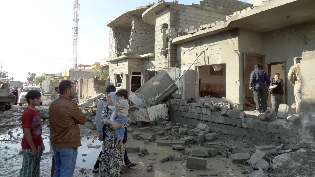 An Iraqi family looks at the damage to a building following one of two car bombs in the northern Iraqi city of Kirkuk, on November 14, 2012.
