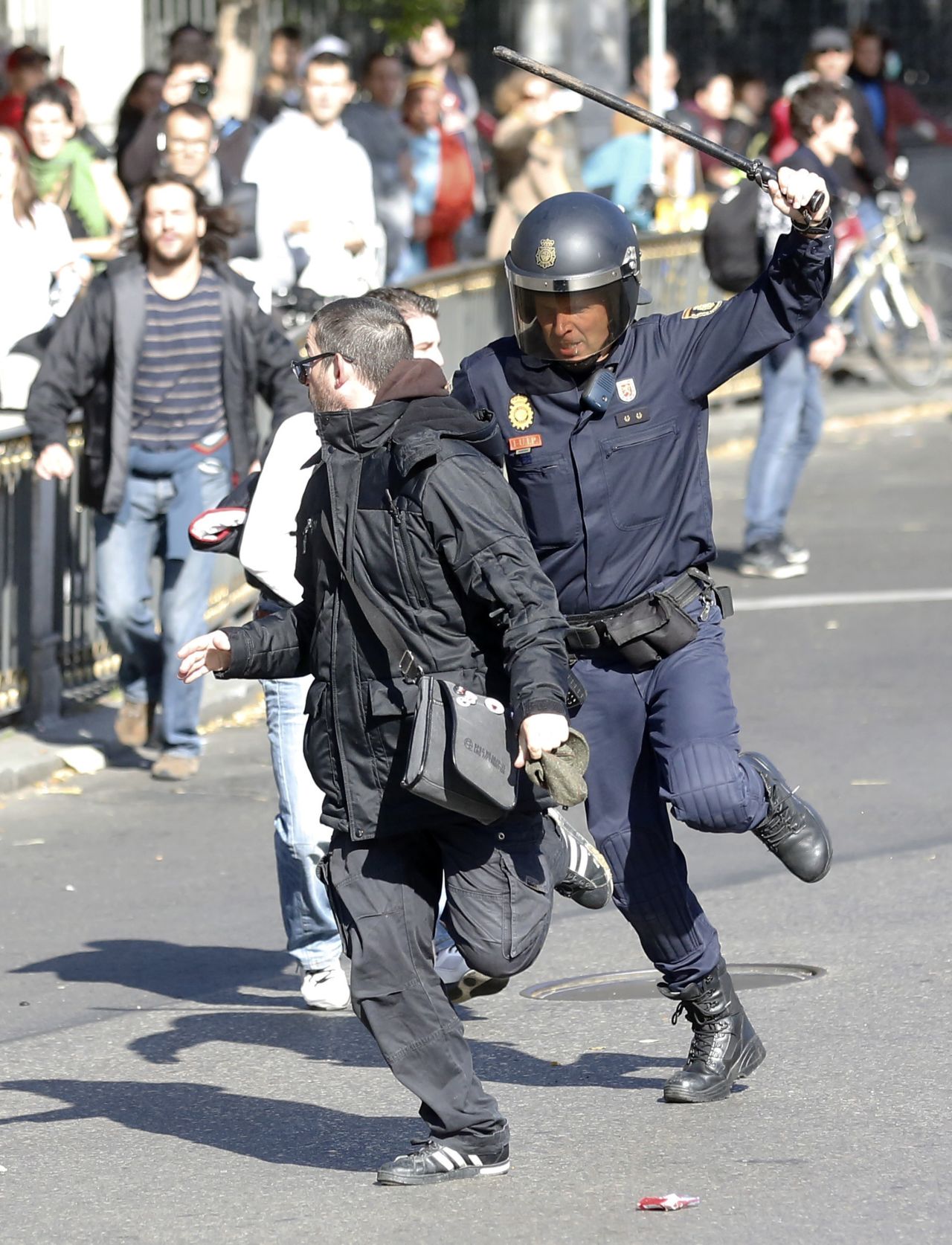 A riot policeman runs after a protester at Cibeles Square in Madrid.