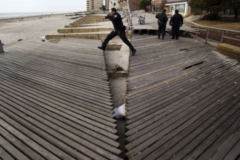 A New York police officer jumps over a large crack in a boardwalk in Brooklyn on Wednesday, November 14. The boardwalk was damaged by the storm surge from Hurricane Sandy.