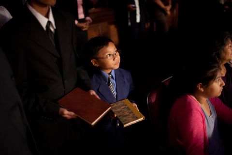 A child lines up with a group of children at First Baptist Church Atlanta, carrying a book written by Charles Stanley. Each child carried one book representing the 45 books written by Stanley during his career. They placed the book on a shelf in front of the sanctuary. 