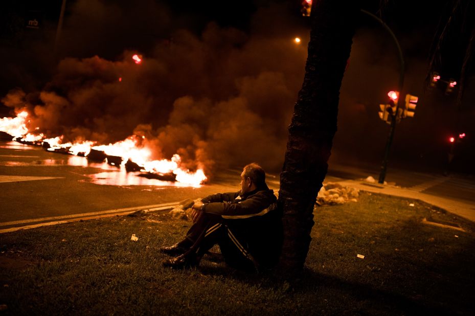 A demonstrator sits next to a barricade of burning tires on November 13, 2012 in Barcelona, Spain.