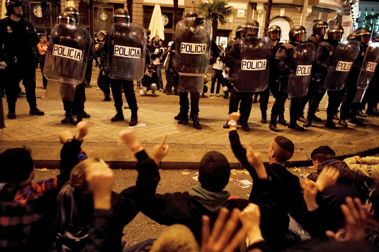 Protesters sit down in front of police Wednesday, November 14, in Madrid, Spain. Demonstrators marched against sweeping austerity measures and high unemployment throughout Europe on Wednesday.