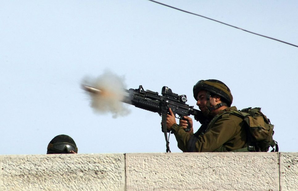 An Israeli soldier fires a tear gas canister toward Palestinian stone throwers on a road mainly used by Israeli settlers in the West Bank village of Beit Omar on Friday, November 16.