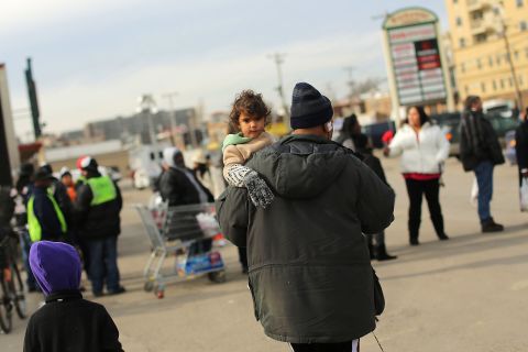 Residents wait for free food in a parking lot in Rockaway on Friday.