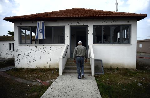 An Israeli man walks to his house damaged by a rocket fired by Palestinian militants from the Gaza Strip in the moshav of Sde Uziyahu near the southern Israeli city of Ashdod.  The Israeli military said it had sealed off all main roads around Gaza and declared a closed military zone, in the latest sign it was poised to launch a first ground offensive on the Palestinian enclave since December 2008-January 2009.