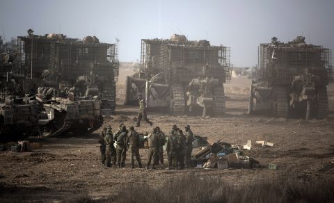 Israeli soldiers gather next to their armored bulldozers stationed on Israel's border with Gaza on Saturday, November 17.