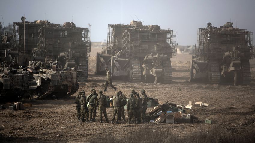 Israeli soldiers gather next to their armoured bulldozers stationed on Israel's border with the Gaza Strip on November 17, 2012. Israeli air strikes destroyed the cabinet headquarters of Gaza's Hamas rulers after militants fired rockets at the heart of Israel which called up thousands more reservists for a possible ground war.