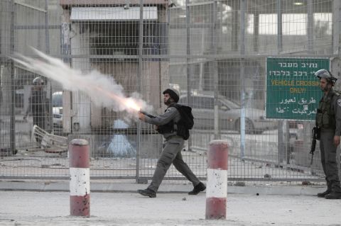 Israeli soldiers fire tear gas toward strone throwers demonstrating against the Israeli military offensive on the Gaza Strip at the Qalandia checkpoint, in the occupied West Bank, on Saturday, November 17. Israeli strikes on Gaza destroyed the Hamas government headquarters as Israel called up thousands more reservists for a possible ground war.