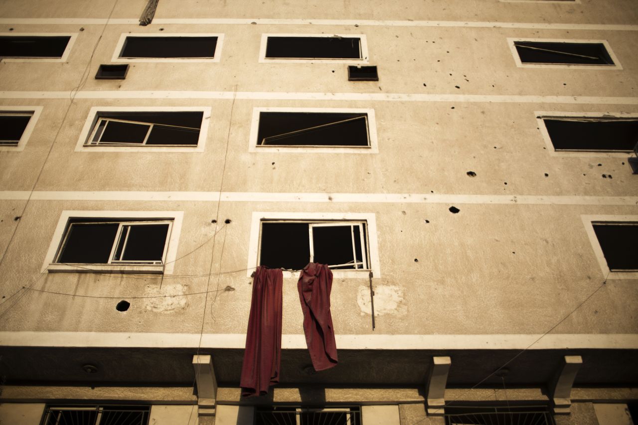 Cloth hangs from a window of a building damaged during Israeli air strikes on Gaza City on Sunday, November 18.