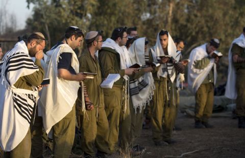 Israeli soldiers wearing prayer shawls conduct morning prayers Sunday, November 18, at an Israeli army deployment area.