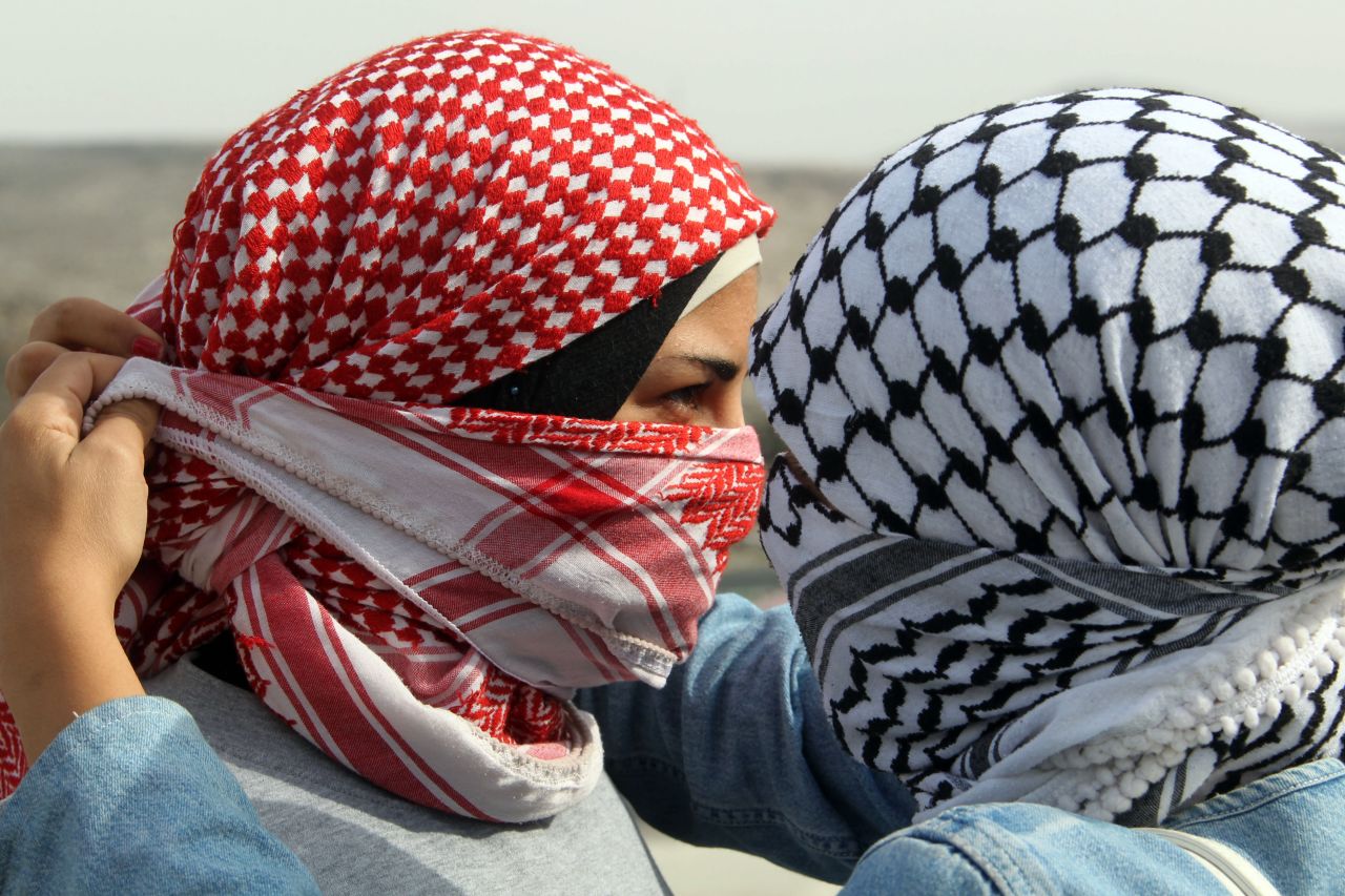 A Palestinian woman helps her friend cover her face with a traditional scarf during clashes at the Hawara checkpoint in the occupied West Bank city of Nablus on Saturday, November 17. People rallied against the Israeli military operations.