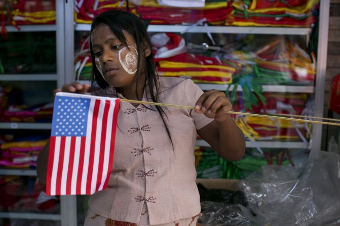 A Burmese woman fixes an American flag onto a wooden stick at a flag shop in Yangon on Sunday.