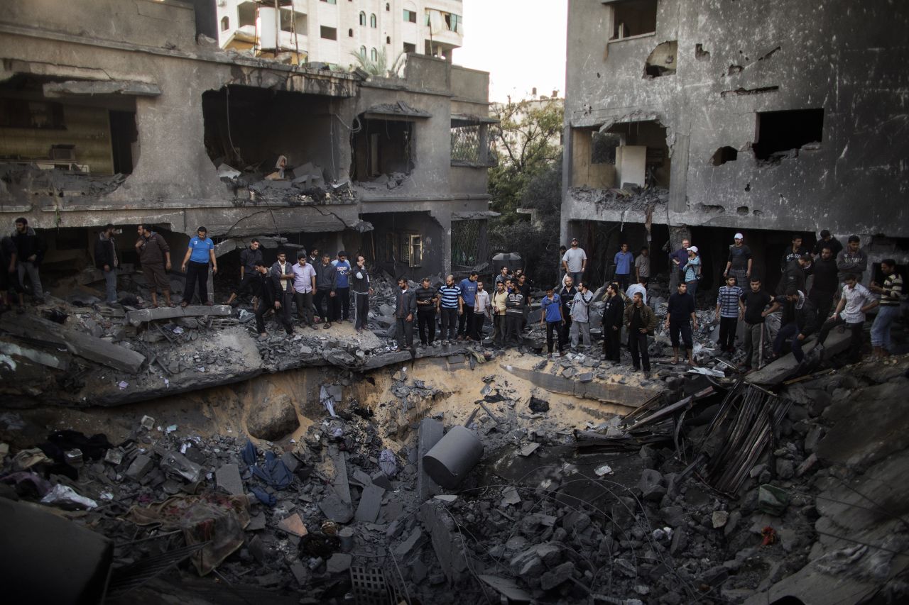 Palestinian men gather around a crater caused by an Israeli airstrike at a home in Gaza City on Sunday, November 18.