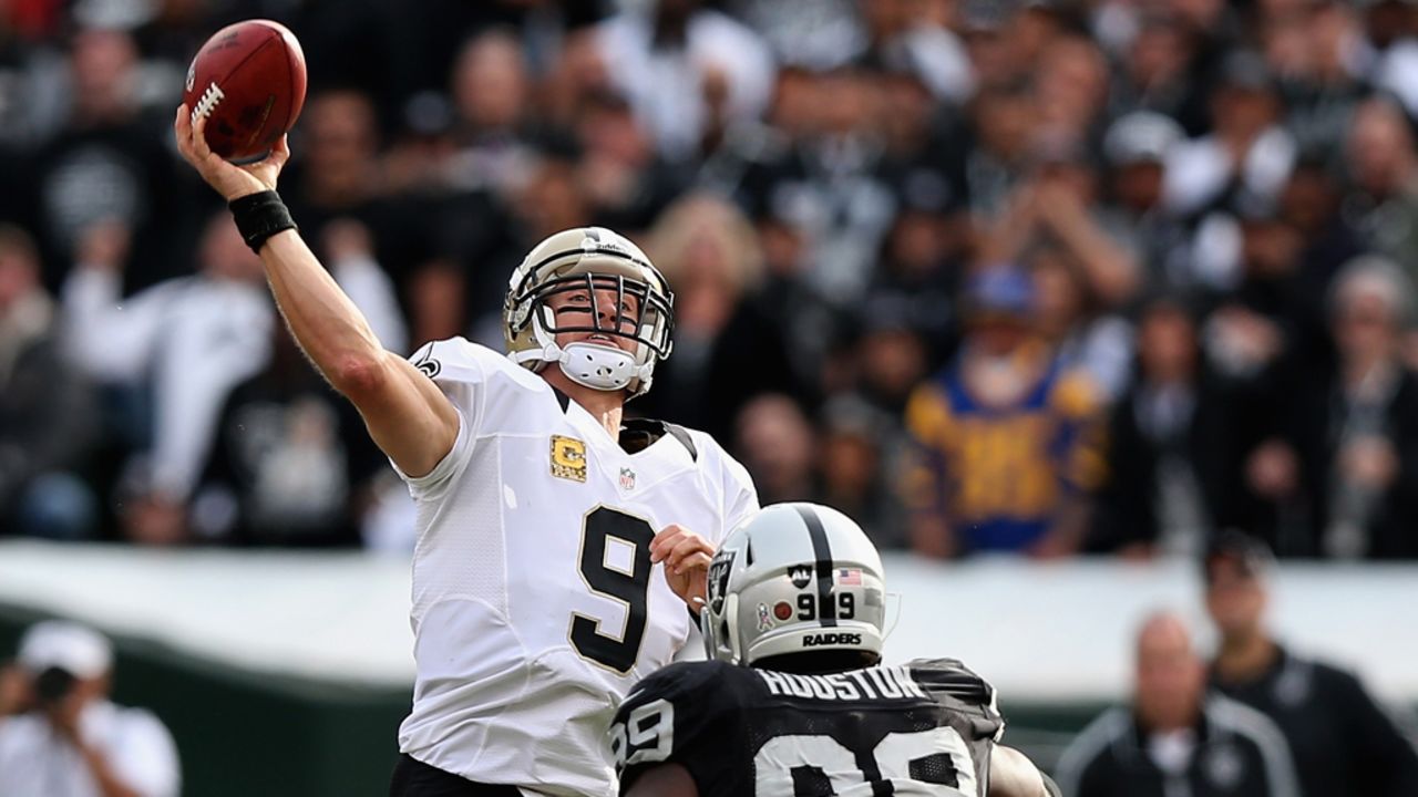 Drew Brees of the New Orleans Saints throws a long touchdown pass to Lance Moore in the second quarter before being hit by Lamarr Houston of the Oakland Raiders at O.co Coliseum on Sunday in Oakland, California.