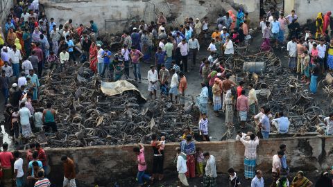 Onlookers gather around the wreckage of fire-damaged rickshaws in a slum in Dhaka, Bangladesh, on Sunday.