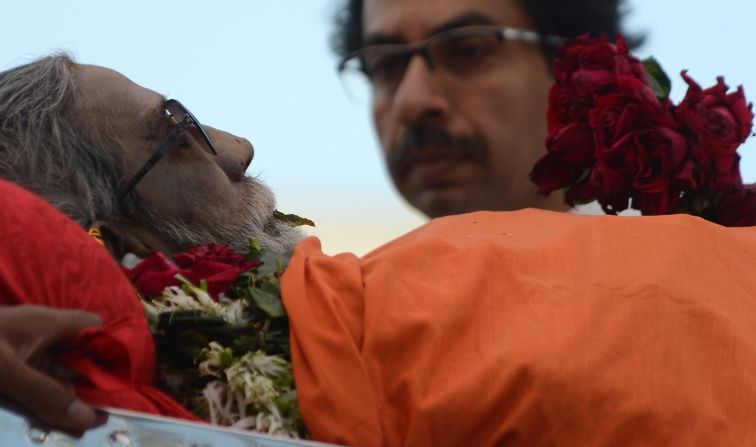 The body of  Bal Thackeray is watched by his son Uddhav Thackeray (R) as it is carried through a sea of supporters during the funeral procession.