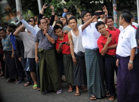 Local residents line up along the street with cameras as Obama's motorcade drives to the Parliament House in Yangon.