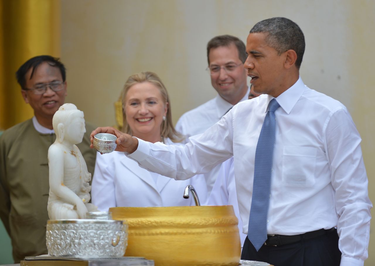 U.S. President Obama performs a ritual as U.S. Secretary of State Hillary Clinton looks on at a visit to the Shwedagon pagoda in Yangon on Monday.