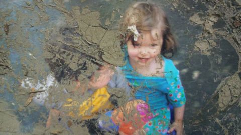 Two colorfully dressed children play in this photograph, caked with mud after Superstorm Sandy.