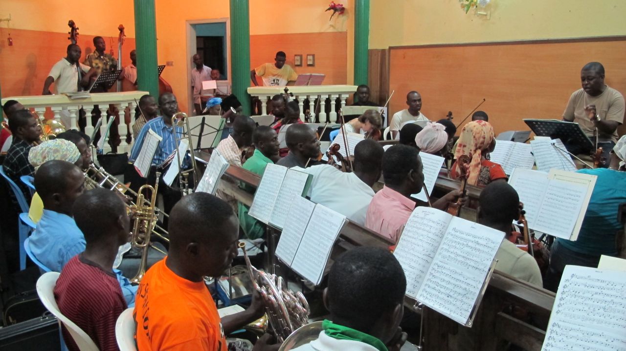 Conductor Armand Diangienda (far right) is the founder and conductor of the Orchestre Symphonique Kimbanguiste. Their rehearsal room, in his house, can barely fit the ensemble of some 200 people.