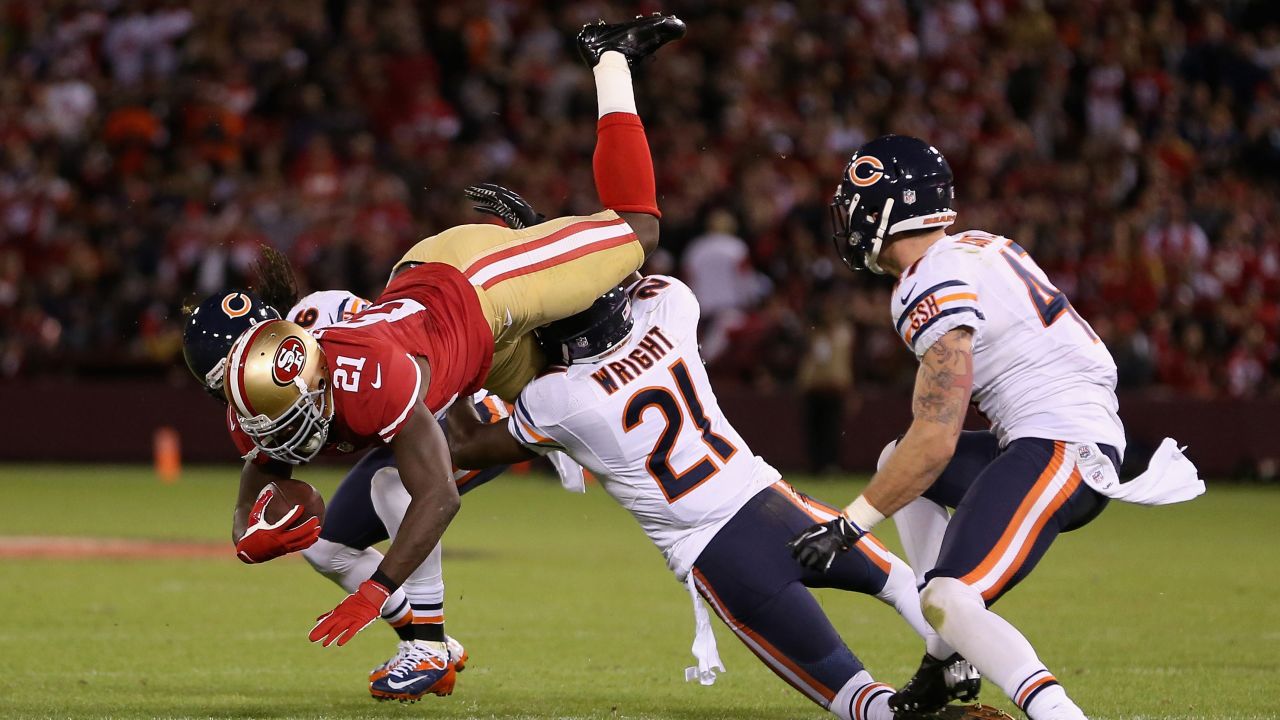 Frank Gore of the San Francisco 49ers tries to leap over Major Wright, center, and Tim Jennings, left, of the Chicago Bears.
