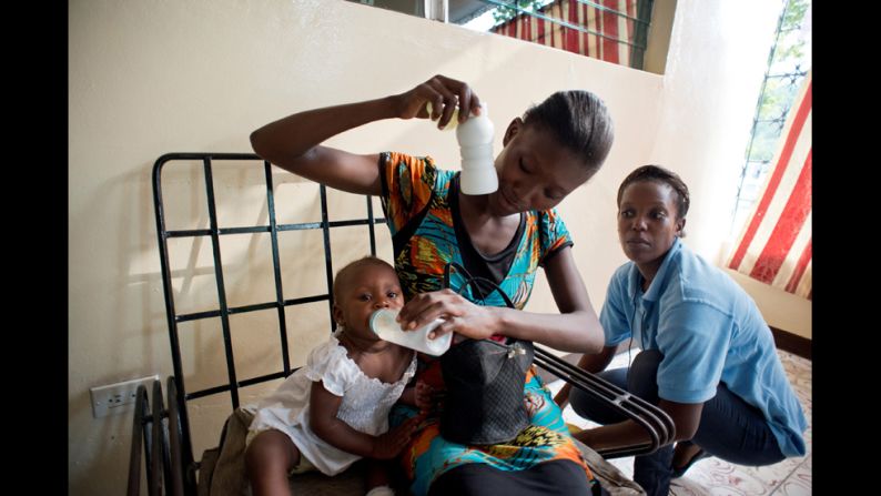 A woman and her baby attend a group meeting at the KOFAVIV center while a employee of the nonprofit looks on.  