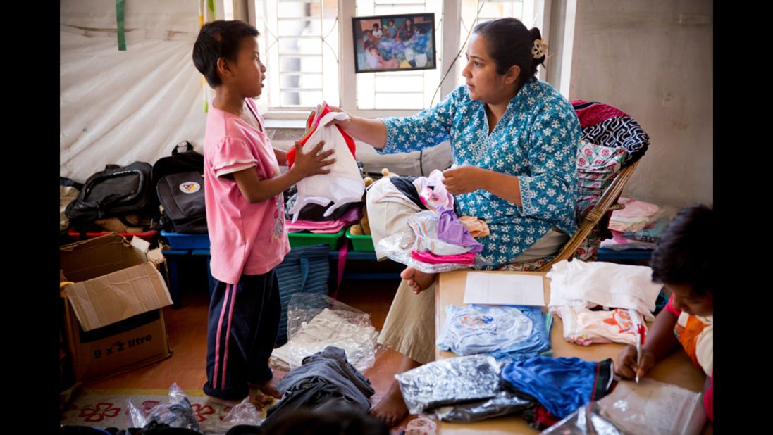 Basnet hands out new clothes to one of the young children she cares for in Kathmandu. The children reciprocate her love by calling her "Mamu," which means "mommy."