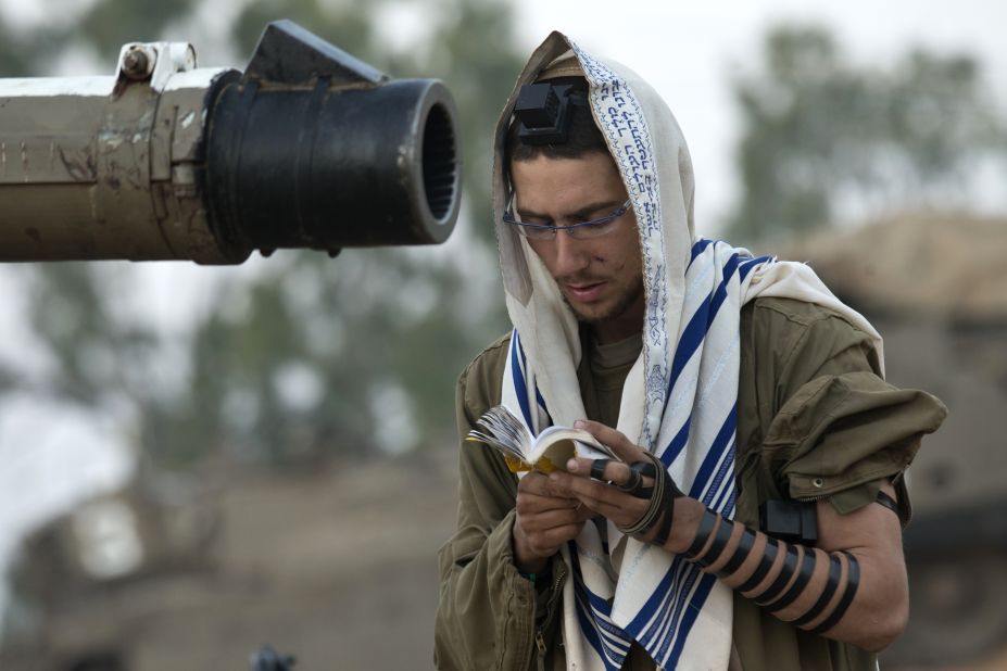 An Israeli soldier reads his morning prayers Tuesday at an Israeli army deployment area near the Israel-Gaza border as they prepare for a potential ground operation in the Palestinian coastal enclave. 